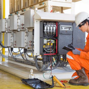 Electrical and instrument technician measuring voltage of thermo electric generator and record reading value to maintenance sheet for annual inspection at offshore oil and gas remote platform.