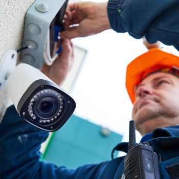 Video surveillance. Technician worker installing wall camera with screwdriver
