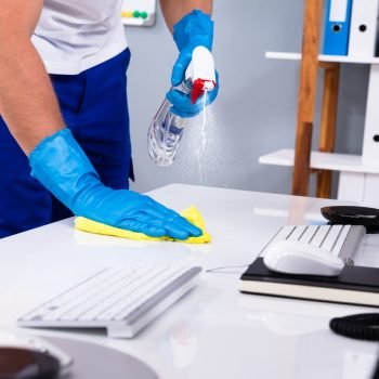 Janitor cleaning white desk in modern office