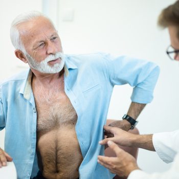 Senior man with a painful back-kidney on a medical exam.